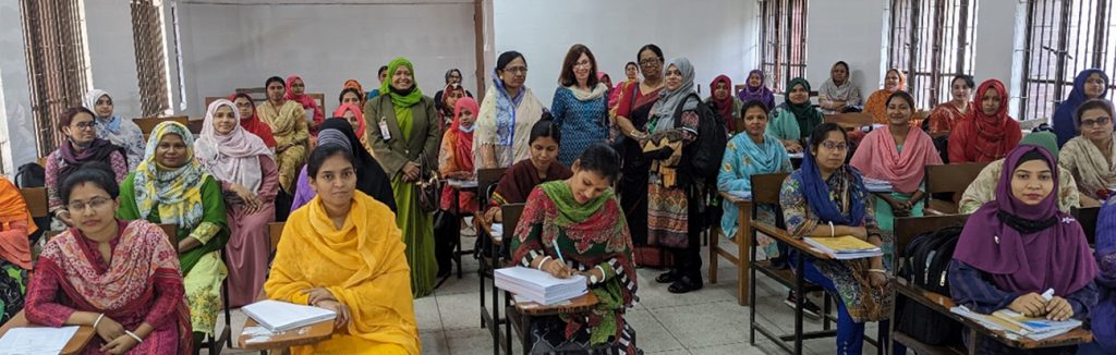 Cynthia Baker, Ph. D. se trouve au milieu d’une grande classe d’enseignantes et d’étudiantes bangladaises assises à des pupitres